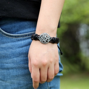 Bracelet vintage en cuir tressé avec breloque fleur en métal ajouré sur le poignet