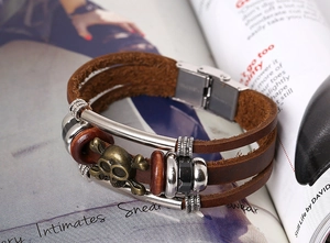 Detail of vintage punk layered leather bracelet with skull and metal tube accents