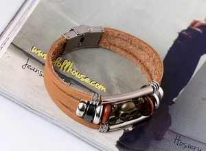 Detailed macro of multi-layer leather bracelet featuring bronze skull and steel clasp