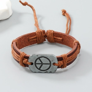 Dettaglio macro del bracciale in pelle marrone con placca in metallo simbolo pace e corda