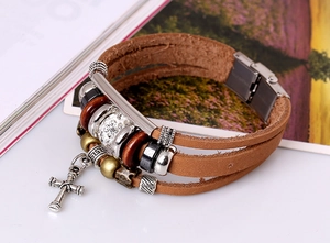 Détail d'un bracelet en cuir multicouche avec pendentif croix en argent et perles métal