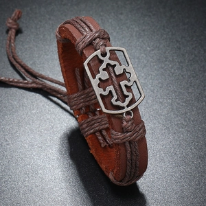 Detail eines handgewebten dunkelbraunen Lederarmbands mit hohlem Kreuz-Metallanhänger