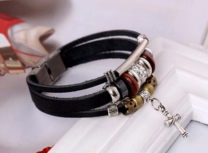 Détail d'un bracelet multicouche en cuir vintage avec pendentif croix et perles
