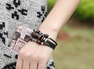 Détail d'un bracelet multicouche en cuir tressé avec perles en bois et alliage sur le poignet