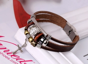 Détail d'un bracelet multicouche en cuir marron avec pendentif croix et perles vintage