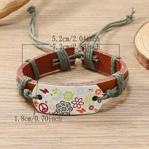 Handmade woven leather bracelet with flower and butterfly patterns on wooden table