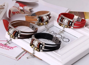 Gros plan de bracelets multicouches en cuir avec breloques croix et fermoir aimanté
