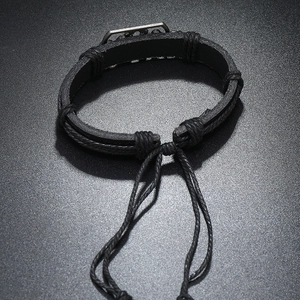 Detail eines handgewebten schwarzen Lederarmbands mit Vintage-Metallplatte und Kordelzug