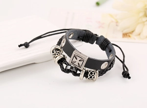 Close-up of multilayer leather bracelet with silver cross pendant and adjustable cord