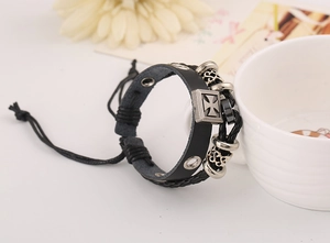 Detail of vintage multilayer leather bracelet with Maltese cross and heart charm