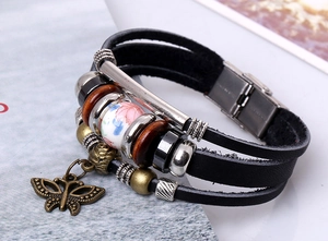 Dettaglio bracciale multistrato in pelle vintage con farfalla di bronzo e perla