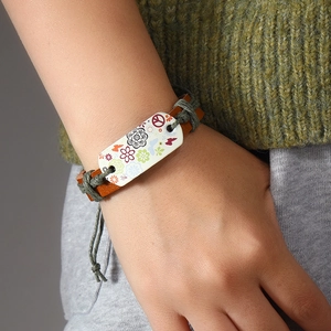 Handmade woven leather flower bracelet with peace sign charm worn on a female wrist
