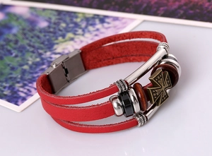 Detail of red multilayer leather bracelet with a bronze cross pendant and magnetic clasp