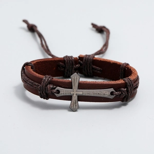 Detail of cross charm on brown leather bracelet with laser engraved Spanish Lord's Prayer