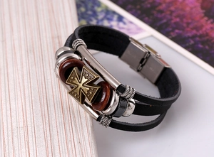 Detail of multilayer leather bracelet with bronze cross, wood beads, and metal clasp