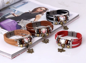 Dettaglio di bracciali in pelle multistrato vintage con perle in ceramica e farfalla