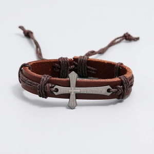 Detail of vintage brown leather bracelet with metal cross and engraved Spanish scripture