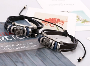 Detail von mehrlagigen Lederarmbändern mit Metallkreuzen und Vintage-Blauperlen