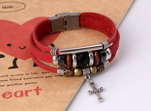 Macro shot of punk leather bracelet with cross pendant and multi-layer bead detailing