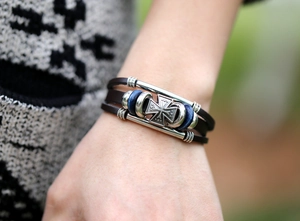 Detailansicht eines mehrlagigen Lederarmbands mit Eisernem Kreuz und blauen Perlen