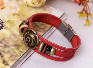 Close-up of vintage red leather multilayer bracelet with bronze rose charm detail
