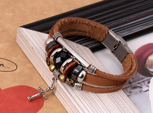 Detail showing multi-layer brown leather bracelet with metal cross pendant and beads