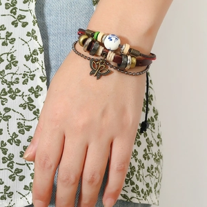 Close-up of multilayer leather bracelet with bronze butterfly charm and ceramic beads