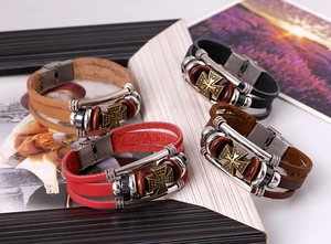 Close-up of multilayer leather bracelets with bronze cross charms in punk style