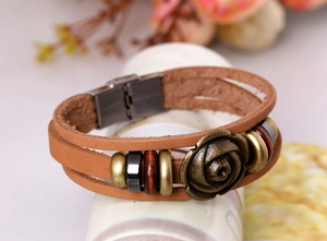 Macro detail of multilayer leather bracelet with bronze rose flower and magnetic clasp