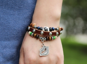 Detail of layered bohemian leather bracelet with colorful beads and a metal lip charm