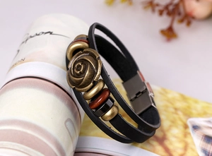 Detail of multi-layer leather bracelet with bronze rose and wooden beads on prop