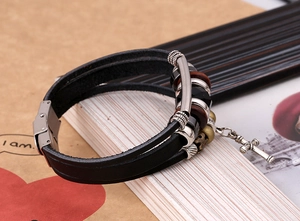 Close-up of multilayer leather bracelet featuring metal cross pendant and wooden beads