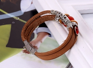 Detail of multi-layer brown leather bracelet with silver floral tubes and red beads