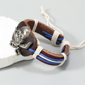 Detail of vintage leather pirate bracelet with silver skull and crossbones emblem