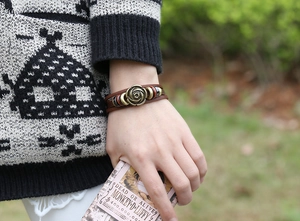 Detail of brown multilayer leather bracelet with a bronze rose and colorful beads