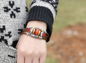 Detailed close-up of multilayer leather bracelet with red beads and bohemian alloy charms