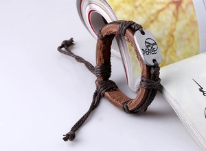 Macro shot of brown leather bracelet with hemp rope and engraved alloy Peace charm