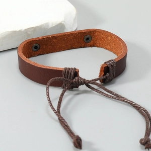 Detail of vintage brown leather bracelet featuring metal rivets and adjustable braided cord