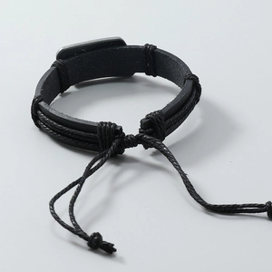 Détail d'un bracelet punk en cuir tressé noir avec plaque métallique et cordon réglable