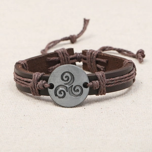 Retro brown leather bracelet featuring a Triskelion metal emblem and woven cord details