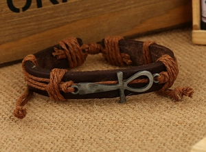 Macro shot of handmade brown leather bracelet with silver Ankh cross and woven hemp cord