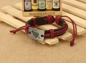 Detail of vintage braided leather bracelet with Cupid arrow metal charm on linen backdrop