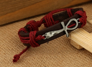 Detail of vintage brown leather bracelet featuring silver Ankh symbol on burlap background