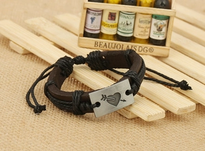 Close-up of retro leather bracelet with heart arrow metal plate on wooden background