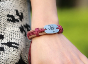 Macro shot of hand-woven leather bracelet with silver Peace plate and hemp rope detail