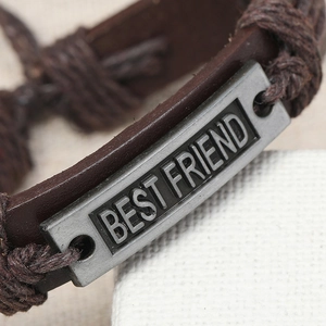 Détail macro d'un bracelet en cuir tressé vintage avec plaque gravée BEST FRIEND