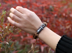 Close-up of vintage multilayer braided leather bracelet with silver Ankh cross symbol