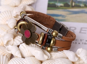 Detail of vintage multilayer leather bracelet with bronze flower charm and wooden beads