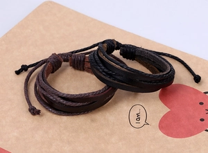 Detail of two-piece layered braided leather bracelets in black and dark brown with adjustable ties