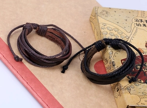 Detail of multi-layer braided leather bracelets in brown and black with adjustable cords